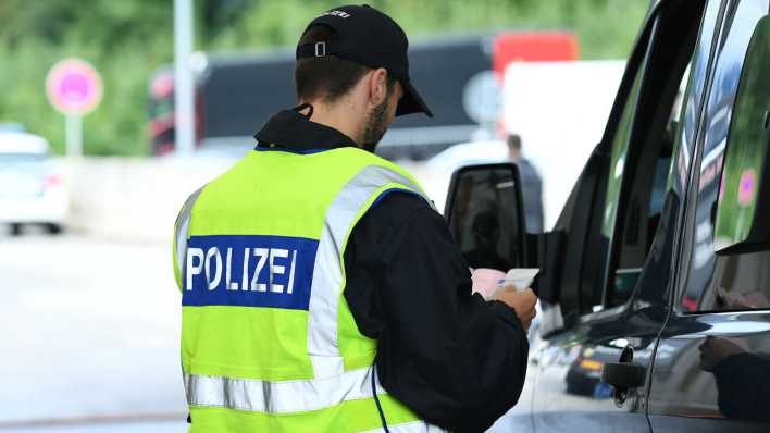 Polizist überprüft einen Fahrer an der deutsch-österreichischen Grenze (Bild: picture alliance/dpa/Revierfoto)