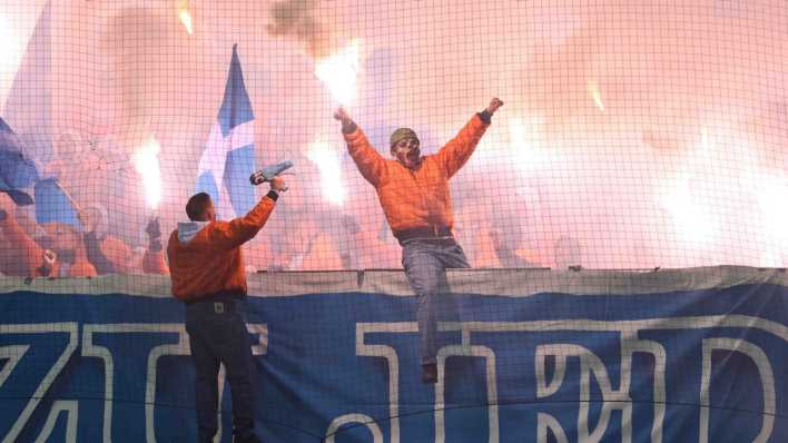 Ein maskierter Fan des FC Hansa Rostock mit einer Pyrofackel in der Hand. (Bild: picture alliance/Fußball-News Saarland/Fabian Kleer)