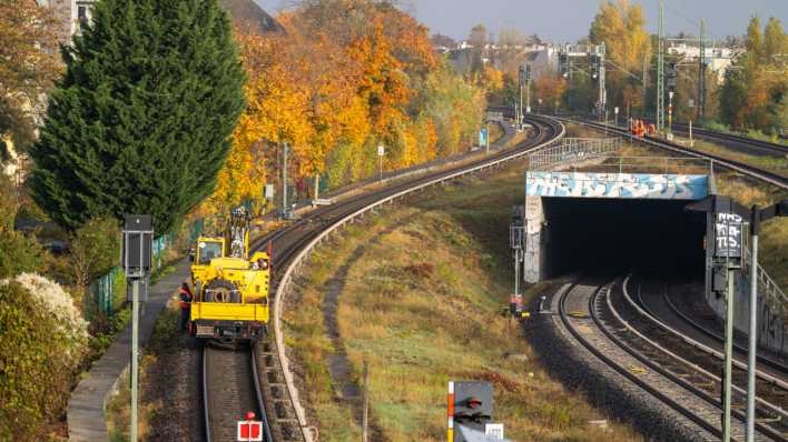 Arbeiter in orangefarbenen Anzügen gehen auf den Gleisen der S-Bahn nahe dem Bahnhof Bornholmer Straße in Berlin. (Bild: picture alliance/dpa/Sören Stache)