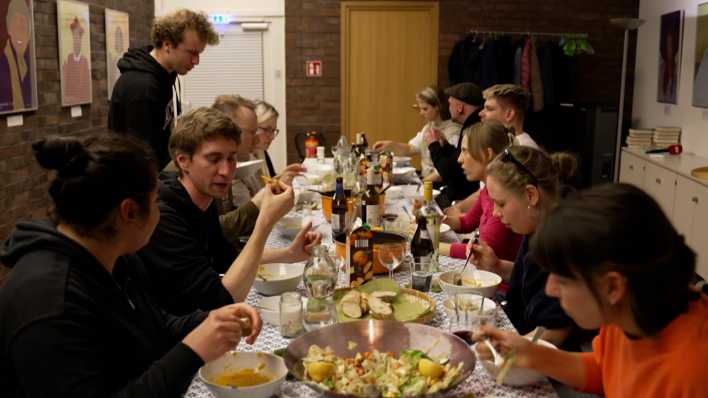 Junge Menschen essen gemeinsam an einem großen Tisch.