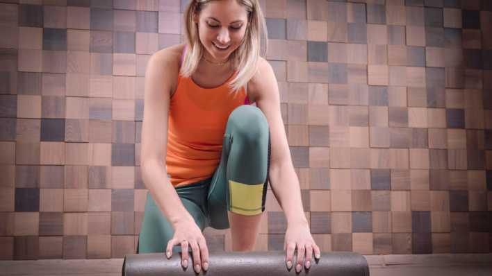 Eine Frau rollt vor dem Training ihre Matte aus. (Bild: picture alliance/imageBROKER/Andy Gin)