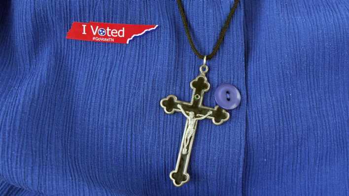 Eine Person trägt eine Kreuz-Kette und einen Anstecker "I Voted".