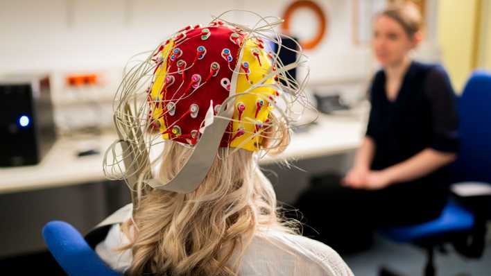 Eine Probandin trägt eine EEG-Haube mit Elektroden für die EEG-Messung (Bild: picture alliance/dpa/Jacob Schröter)