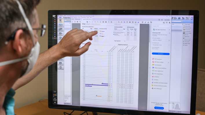 Ein Facharzt arbeitet während eines Pilotversuchs mit einer Patientenakte