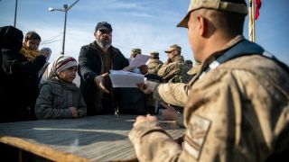 Ein syrischer Mann übergibt einem türkischen Gendarmen am Cilvegozu Grenzübergang in der Nähe der südtürkischen Stadt Antakya Dokumente, um von der Türkei nach Syrien einreisen zu können. (Bild: picture alliance/dpa/AP/Metin Yoksu)