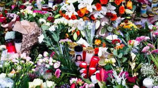 Blumen und Kerzen liegen vor der Johanniskirche in der Nähe des Weihnachtsmarkts in Magdeburg.