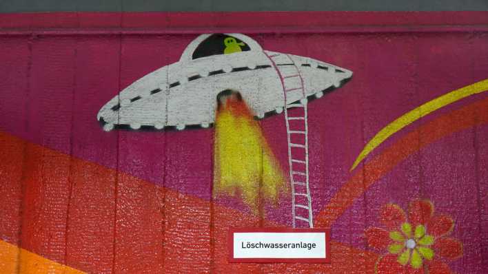 Ein Graffito mit einem UFO befindet sich über dem Schild Löschwasseranlage.