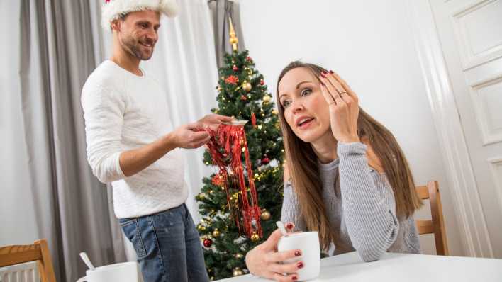 Ein Mann und eine Frau schmücken einen Christbaum und streiten sich (Bild. picture alliance / dpa-tmn / Christin Klose)