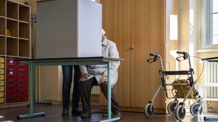 Ein ältere Wählerin mit Begleitung gibt ihre Stimme für die Bundestagswahl ab in einem Wahllokal in Potsdam