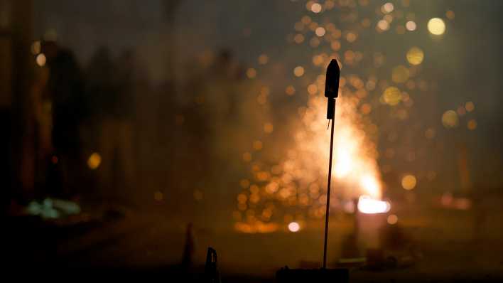 Eine Rakete und Funken sprühendes Feuerwerk an Silvester in Köln.