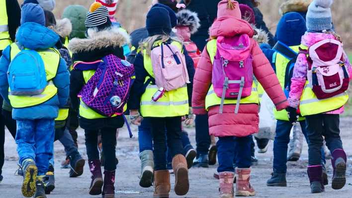 Schüler einer ersten Klasse einer Grundschule folgen bei einem Klassenausflug an einem Januartag ihrer Lehrerin.