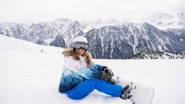 Frau in Ski-Kleidung sitzt im Schnee