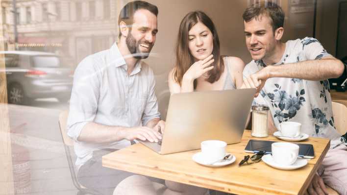 Gruppe von Freunden im Café um einen Computer