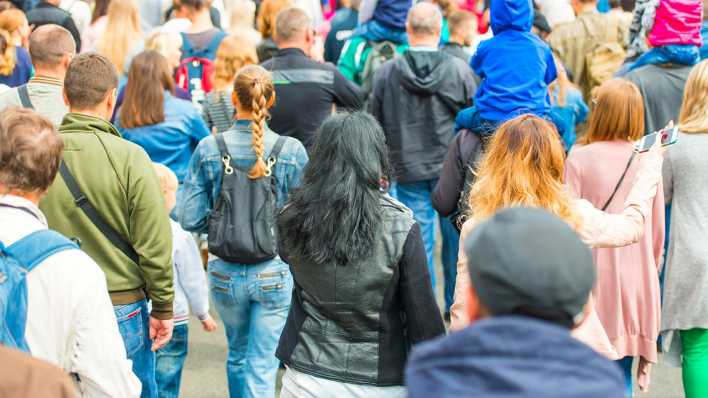 Viele Menschen laufen auf der Straße und sind von hinten zu sehen.