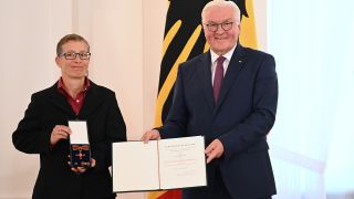 Bundespräsident Frank-Walter Steinmeier überreicht eine Auszeichnung an Übersetzerin Claudia Dathe bei der Verleihung des Verdienstordens der Bundesrepublik Deutschland (Bild: picture alliance/dpa/Britta Pedersen)