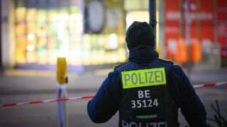 Ein Polizist steht an einem Tatort vor einem Absperrband.