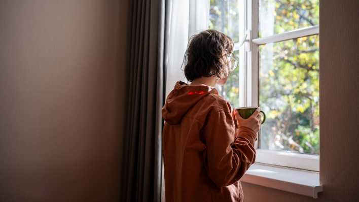 Einsame junge Frau sieht aus dem Fenster