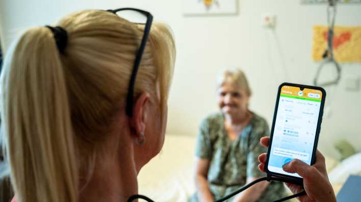 Pflegerin mit Patientin und der App Voize auf dem Smartphone