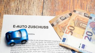 Symbolbild Zuschuss für E-Autos: Geldscheine und Spielzeugauto