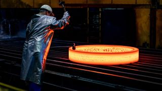 Ein Mitarbeiter stempelt im ThyssenKrupp Werk Rothe Erde einen glühenden Rohling.